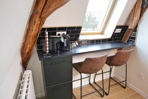 a tiny kitchen with a black counter and stools at Villa Noellet - Clermont Ferrand in Aubière