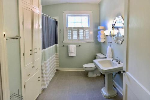 a bathroom with a toilet and a sink and a window at KING BED Family Friendly Cottage - Walk to Zoo & Waterpark - Near Downtown & Midtown in Hattiesburg