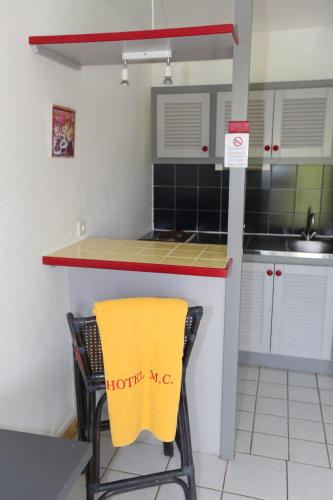 a kitchen with a counter with a yellow towel on a chair at Hotel La Maison Creole in Le Gosier