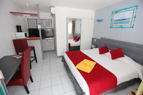 a bedroom with a bed and a desk and a kitchen at Hotel La Maison Creole in Le Gosier