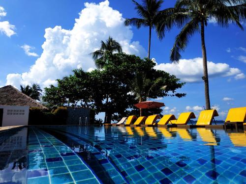 a swimming pool with yellow chairs and palm trees at Serenity Resort Koh Chang in Ko Chang