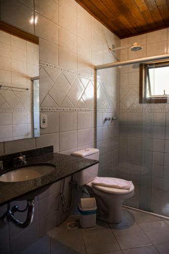 a bathroom with a toilet and a sink and a shower at Pousada Aracê in Pedra Azul