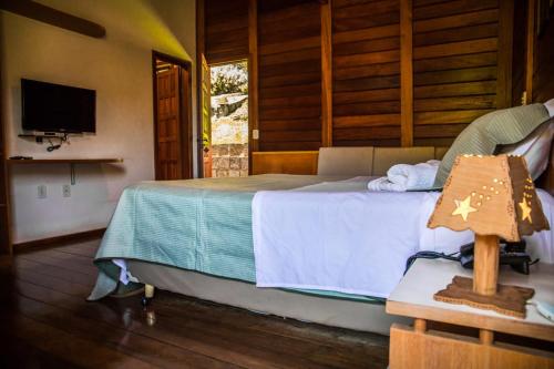 a bedroom with a bed with a television and a bed sidx sidx sidx at Pousada Aracê in Pedra Azul