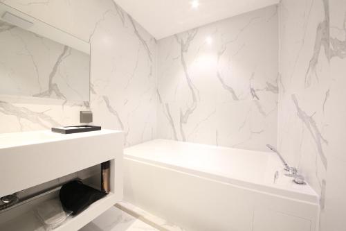 a white bathroom with a white tub and a sink at Zam 101 in Busan
