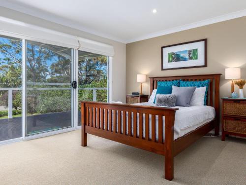 a bedroom with a bed and a large window at Akarana Beach House by Jervis Bay Rentals in Vincentia