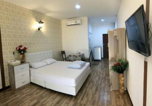 a bedroom with a white bed and a flat screen tv at Tamruethai House - ตามฤทัยเฮาส์ in Chiang Mai
