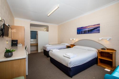 a hotel room with two beds and a television at Blue Seas Motel in Port Lincoln