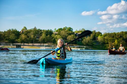 a little girl in a kayak on a lake at Luxury Lakefront Chalet Resort 2 Pools FREE Amenities Dock Kayaks Waterslide in Lampe