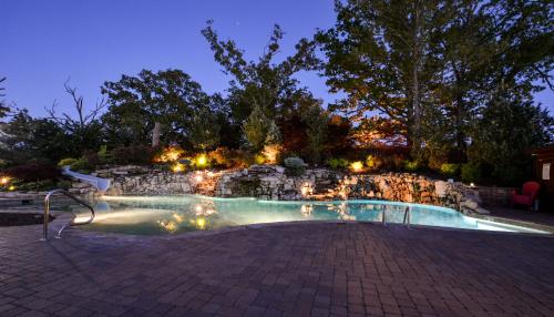 a swimming pool at night with a stone wall at Luxury Lakefront Chalet Resort 2 Pools FREE Amenities Dock Kayaks Waterslide in Lampe