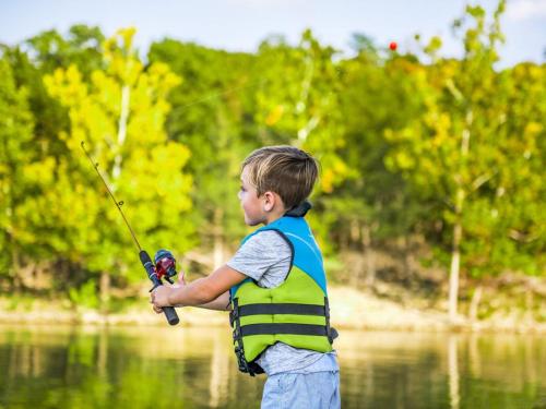 a boy in a vest holding a fishing rod in the water at Luxury Lakefront Chalet Resort 2 Pools FREE Amenities Dock MiniGolf Waterslide in Lampe