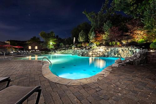 a swimming pool at night with a stone wall at Luxury Lakefront Chalet Resort 2 Pools FREE Amenities Dock MiniGolf Waterslide in Lampe