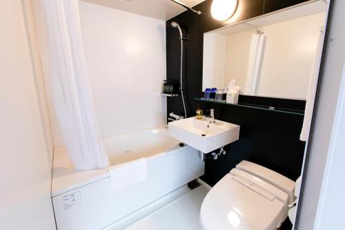 y baño con aseo blanco y lavamanos. en Hotel Wing International Shimbashi Onarimon, en Tokio