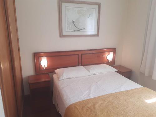 ein Schlafzimmer mit einem Bett mit zwei Nachttischen und einem Bild in der Unterkunft Apartment on Oscar Freire by Paulista and Clínicas in São Paulo