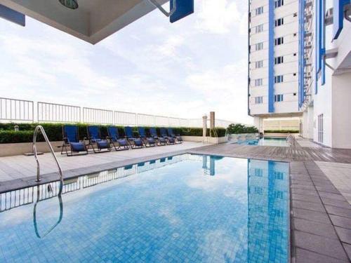 une piscine avec des chaises et un bâtiment dans l'établissement Luxury Condo-Princeton Residence-New Manila Quezon City, à Manille