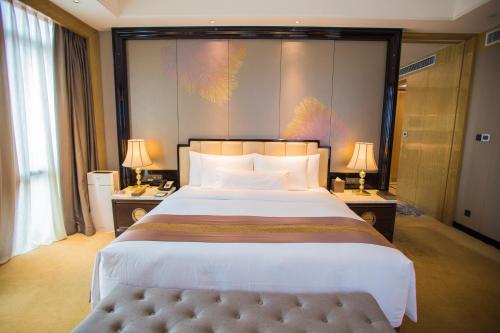a bedroom with a large bed with two tables and two lamps at Wanda Vista Quanzhou in Quanzhou