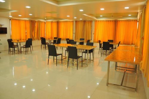 a dining room with tables and chairs and orange curtains at Hotel Shiva's Inn in Trimbak
