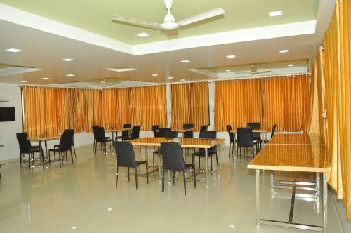 a conference room with tables and chairs and orange curtains at Hotel Shiva's Inn in Trimbak
