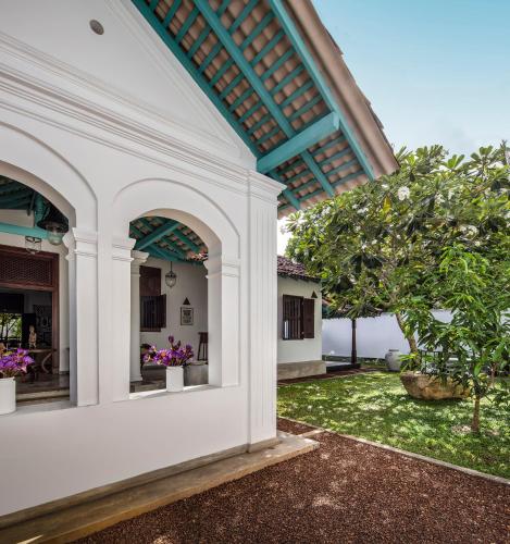 an external view of a white building with a tree at Green Casa in Galle