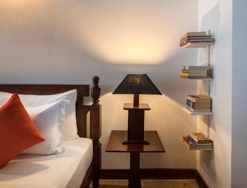 a lamp on a table next to a bed at Green Casa in Galle
