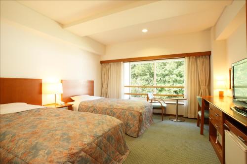 a hotel room with two beds and a window at Kyukamura Iwate-Amiharionsen in Shizukuishi