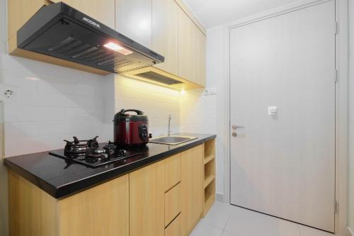 a small kitchen with a stove and a sink at Modern Studio @ Springlake Summarecon Apartment By Travelio in Rawabugel