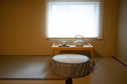 a room with a table and a stool and a window at Onya Kaede in Kyoto