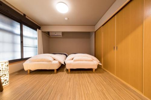 2 Betten in einem Zimmer mit Fenster in der Unterkunft Kyomachiya House IZO in Kyoto