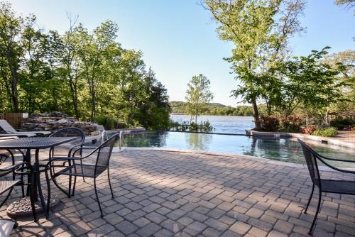 a patio with a table and chairs next to a body of water at Luxury Lakefront Chalet Resort 2 Pools FREE Amenities Dock Kayaks Waterslide in Lampe