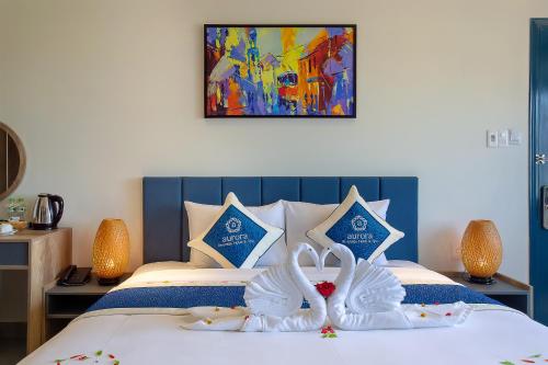 two white swans are sitting on a bed at Hoi An Aurora Riverside Hotel and Spa in Hoi An