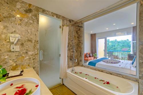 a bathroom with a tub and a sink and a bedroom at Hoi An Aurora Riverside Hotel and Spa in Hoi An