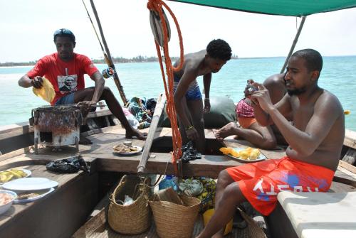 a group of men sitting on a boat in the water at Shella White House in Lamu