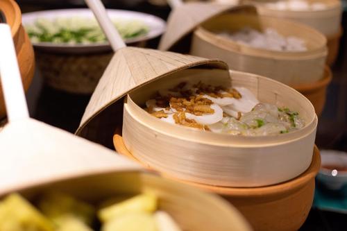 a bowl of food on a table with other dishes at Hoi An Aurora Riverside Hotel and Spa in Hoi An