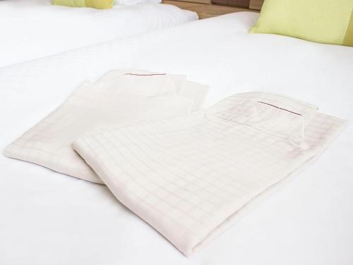 a white t shirt laying on a white bed at Hearton Hotel Nishi Umeda in Osaka
