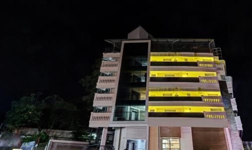a tall building with yellow windows at night at Itsy By Treebo - Dew Dreams in Cochin
