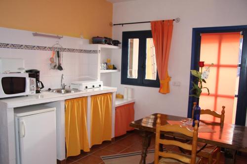 a small kitchen with a table and a microwave at L'Almàssera Casa Rural & Restaurant in Margarida