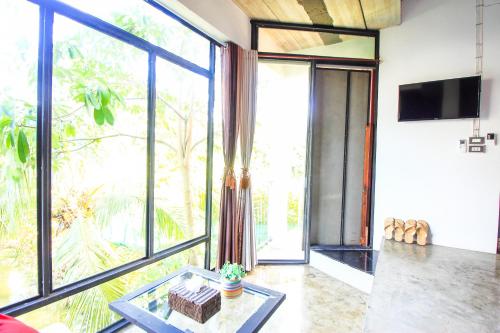a living room with a large window and a table at Plernsalaya resort in Salaya
