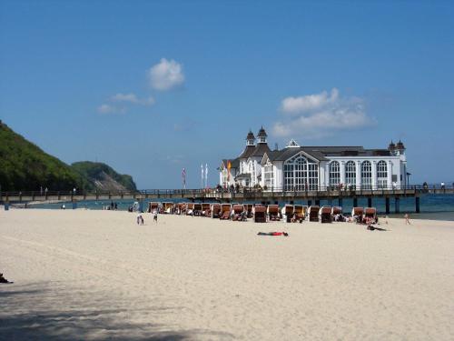 a beach with a pier with chairs and people on it at Ferienappartements unterm Reetdach in Sandort