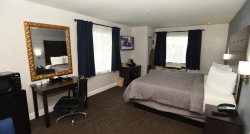 a hotel room with a bed and a desk and a mirror at FairBridge Hotel Atlantic City in Galloway