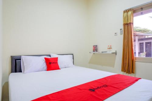 - une chambre avec un lit blanc et un oreiller rouge dans l'établissement RedDoorz near GOR Satria 3, à Purwokerto
