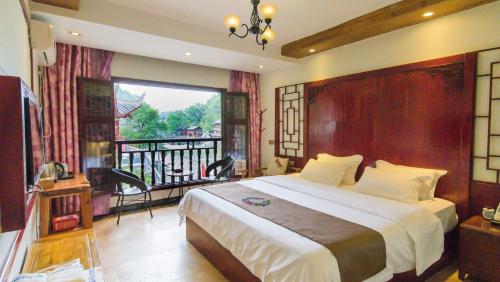a bedroom with a large bed and a balcony at Fenghuang Tujia Ethnic Minority River View Hotel in Fenghuang