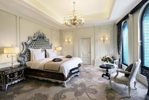 a bedroom with a large bed and a chandelier at Ambassadori Tbilisi Hotel in Tbilisi City