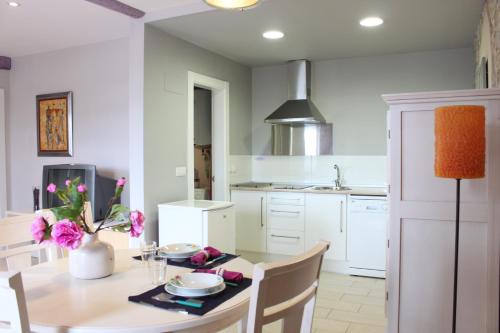a kitchen with a table and chairs and a kitchen with white cabinets at Alojamientos Montesal in Suances
