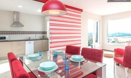 a dining room with a glass table and red chairs at Alojamientos Montesal in Suances