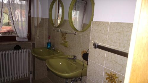 La salle de bains est pourvue de 2 lavabos verts et de 2 miroirs. dans l'établissement Ferienhaus Frankenhöhe, à Diebach
