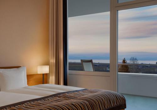 a bedroom with a bed and a large window at Oberwaid - Das Hotel. in St. Gallen
