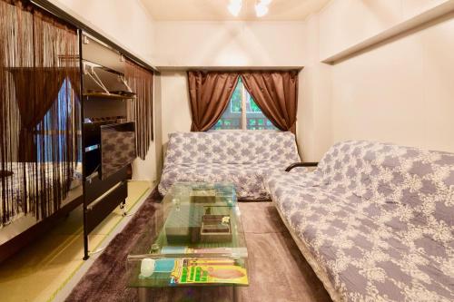 a living room with a couch and a glass table at Holiday Homes TSUBOYA 202 in Naha