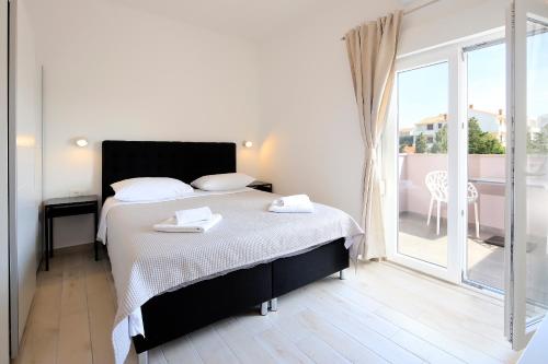 a bedroom with a bed and a large window at Apartments Lola in Novalja