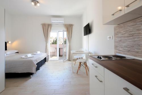 a hotel room with a bed and a kitchen and a room at Apartments Lola in Novalja