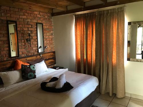 ein Schlafzimmer mit einem Bett und einer Ziegelwand in der Unterkunft Weltevreden Game Lodge in Bloemfontein