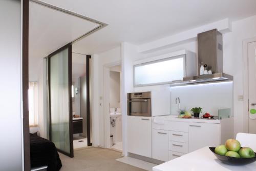 a kitchen with white cabinets and a sink and a mirror at Miró Studio Apartments Dubrovnik in Dubrovnik